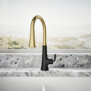 Gold and black kitchen faucet on a marble countertop with a neutral background