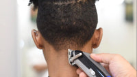 Person using a hair trimmer on their head with a blurred background