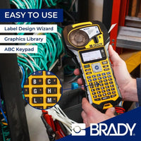 The Brady label printer is held by a person with labeled functions and the BRADY brand name.