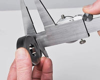 Caliper being used to measure a small object with a plain background