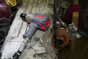 Gray and red impact wrench on a workbench in a workshop setting