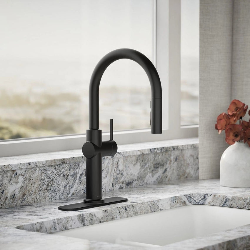 Black kitchen faucet on a marble countertop with a window in the background