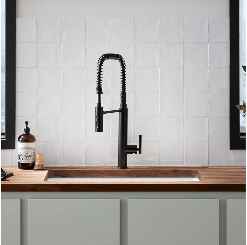 Kitchen faucet over a wooden countertop with a tiled wall background