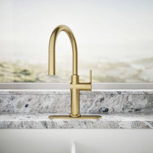 Gold kitchen faucet on a marble countertop with a neutral background
