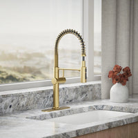 Gold kitchen faucet on a marble countertop with a vase of flowers in the background.