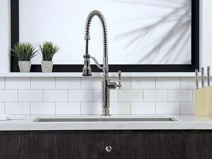 Kitchen sink with a modern faucet against a white tiled wall.