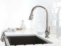 Modern kitchen sink with a silver faucet against a white tiled wall.