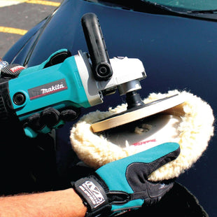 Person using a Makita polisher on a car in a parking lot