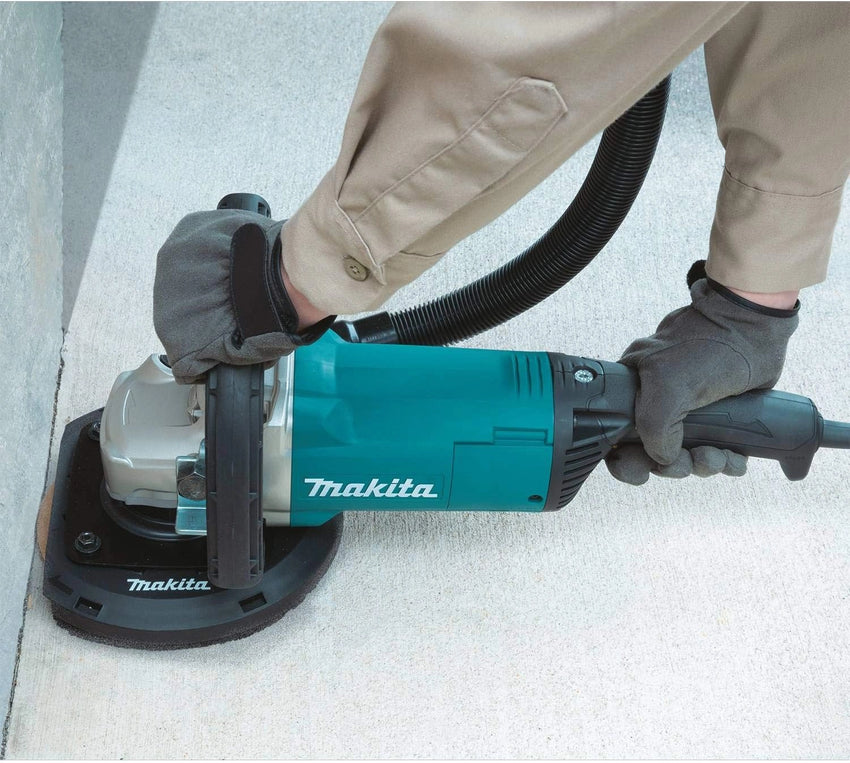 Person using a Makita power sander on a concrete surface