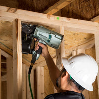 Person using a nail gun in a wooden construction setting