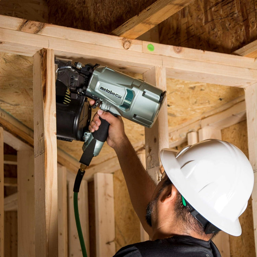 Person using a nail gun in a wooden construction setting