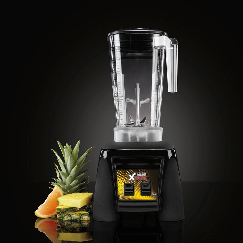 Black blender with a clear container on a black background, featuring a pineapple.